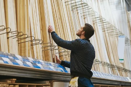 Person sucht in einem Baumarkt Holz aus.